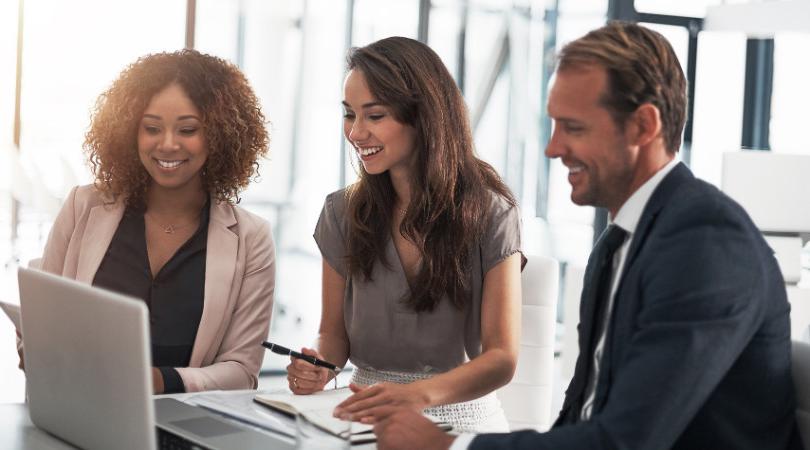 Three people sit around a laptop.